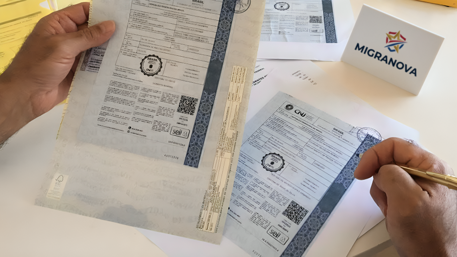 Hands holding apostilled Brazilian documents with official seals, on a desk