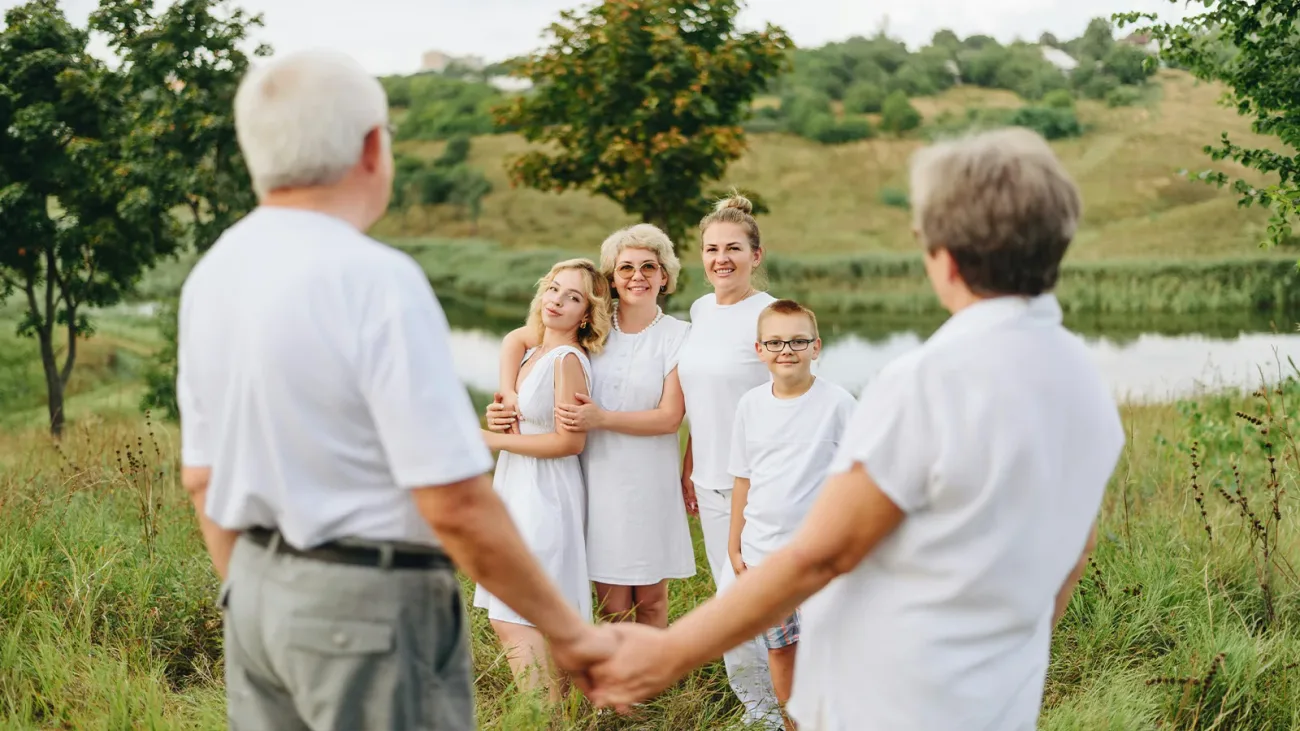 Three-generation family holding hands in a circle in an open field